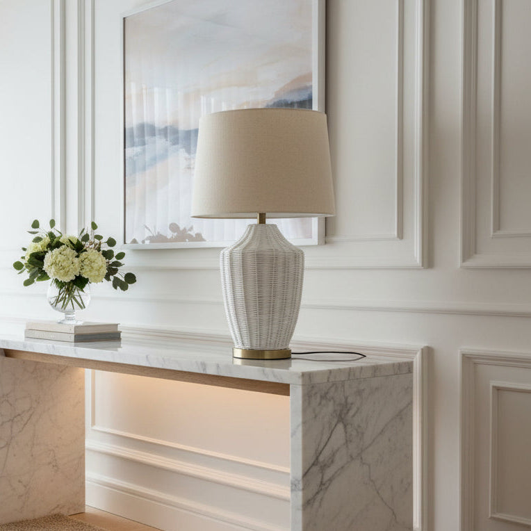 Decorative lamp with wicker base and beige shade on a white background