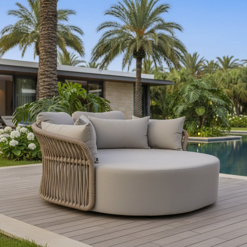 Round outdoor sofa with wicker frame and cushions on a white background