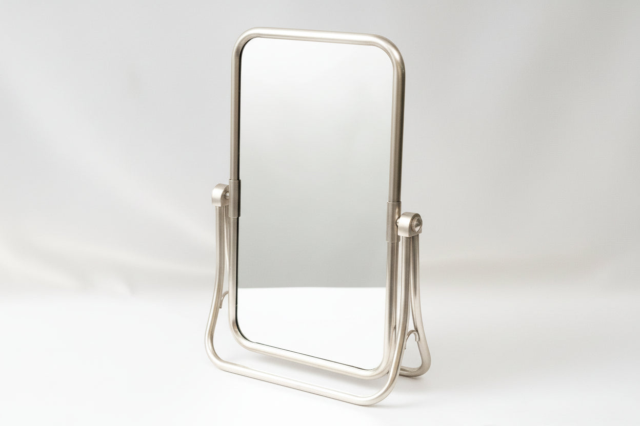 Silver-framed makeup mirror on a white background
