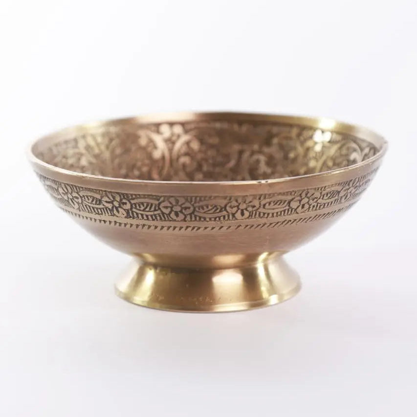 Decorative brass bowl with intricate patterns on a white background