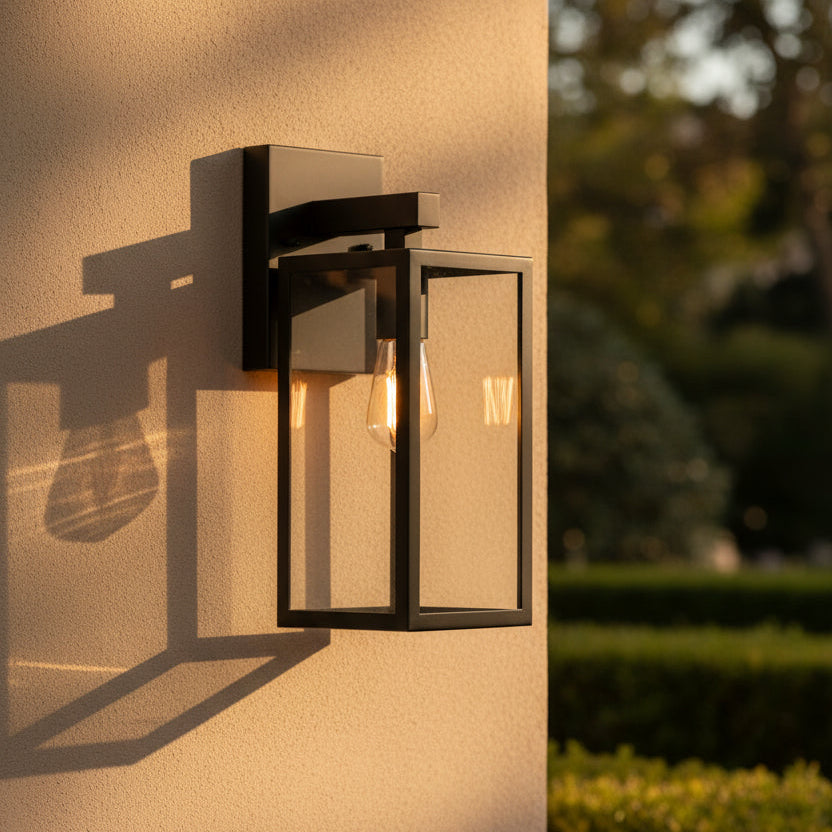 Black outdoor wall light fixture with clear glass cover on a white background