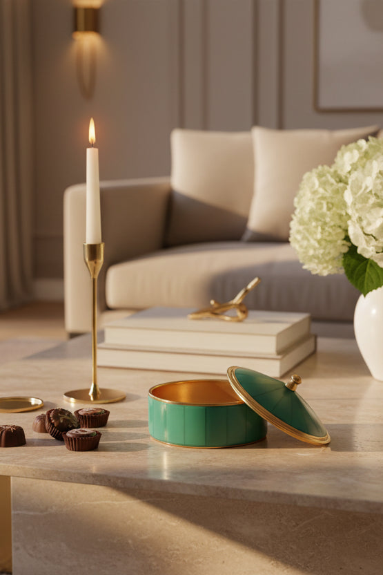 A small round lidded box with a glossy turquoise green body and lid, accented by gold trim and a gold finial on top, shown on a plain white background.