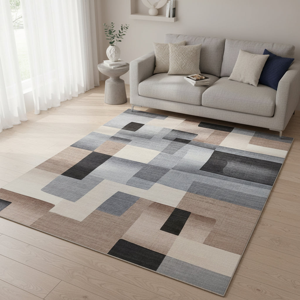 An abstract geometric area rug featuring a modern block pattern in shades of gray, beige, brown, and charcoal black.