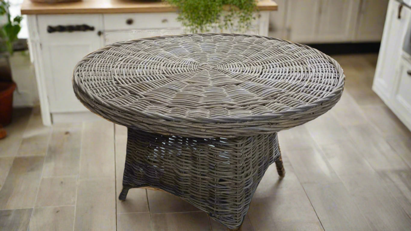 Wicker furniture set including a table and chairs in an indoor setting.