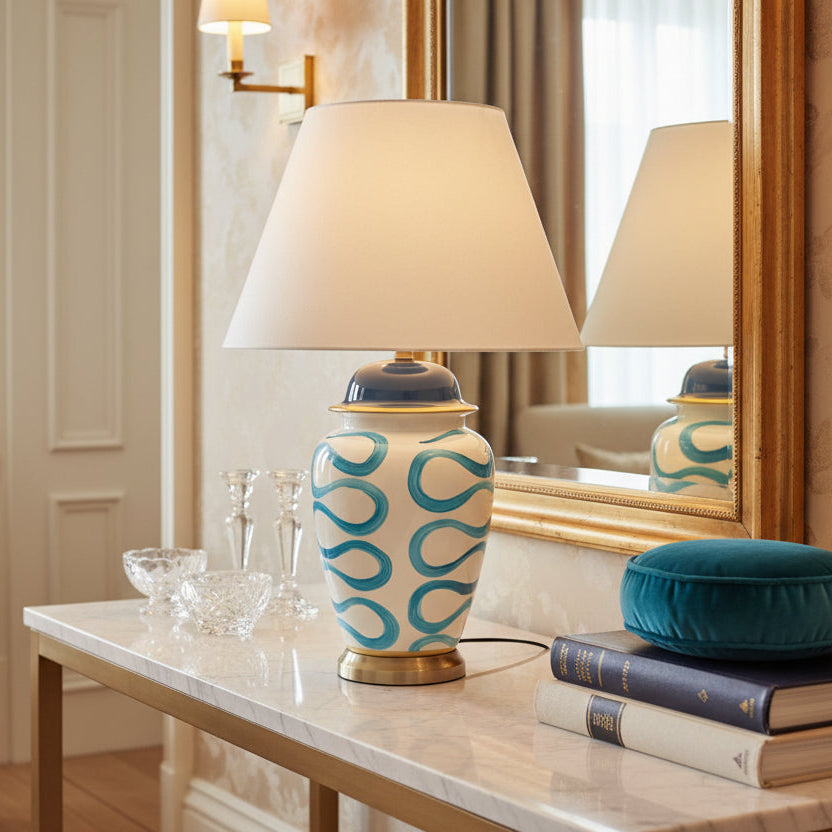 Decorative lamp with white shade, blue and white patterned base, and blue accent on a light gray background