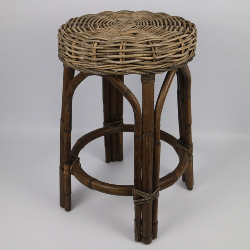 A rustic wicker and bamboo bar stool with a round woven seat, dark brown bamboo legs, and a circular footrest, photographed on a neutral light gray background.