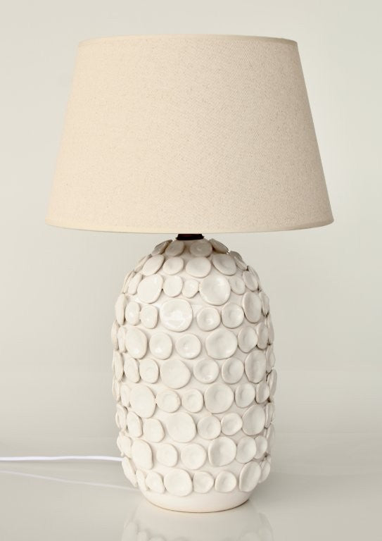 Table lamp with textured ceramic base and beige lampshade on a light background