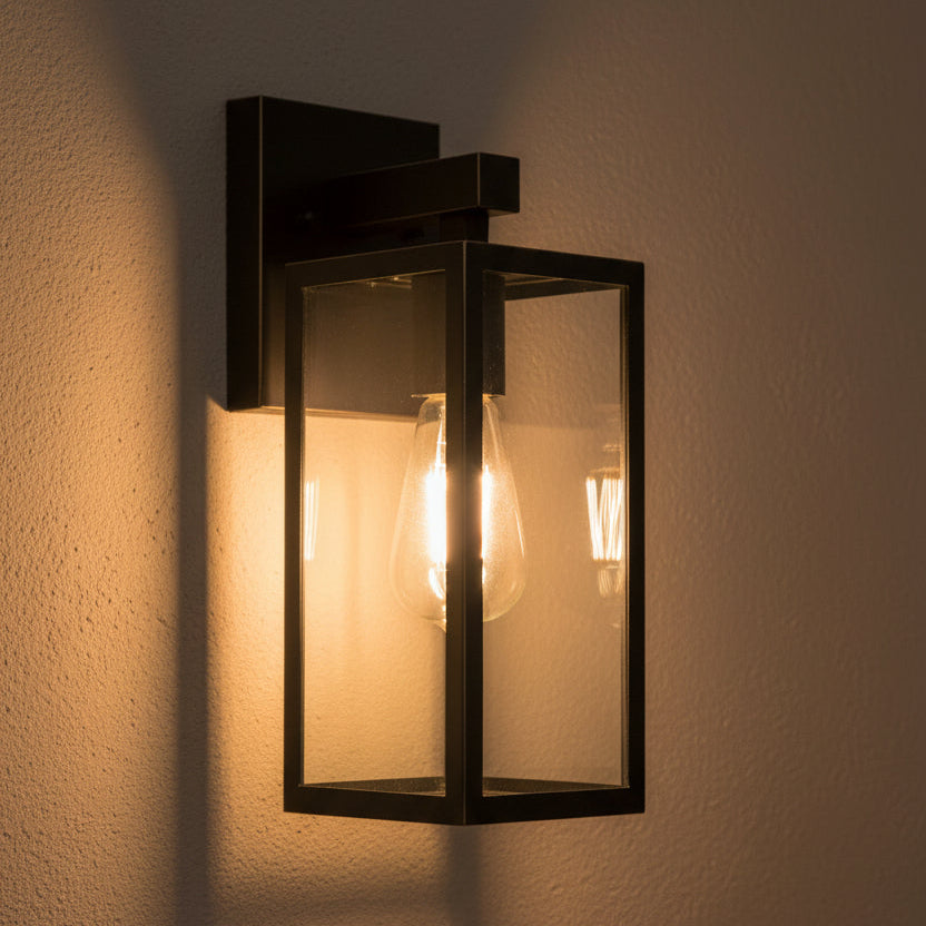 Black outdoor wall light fixture with clear glass cover on a white background