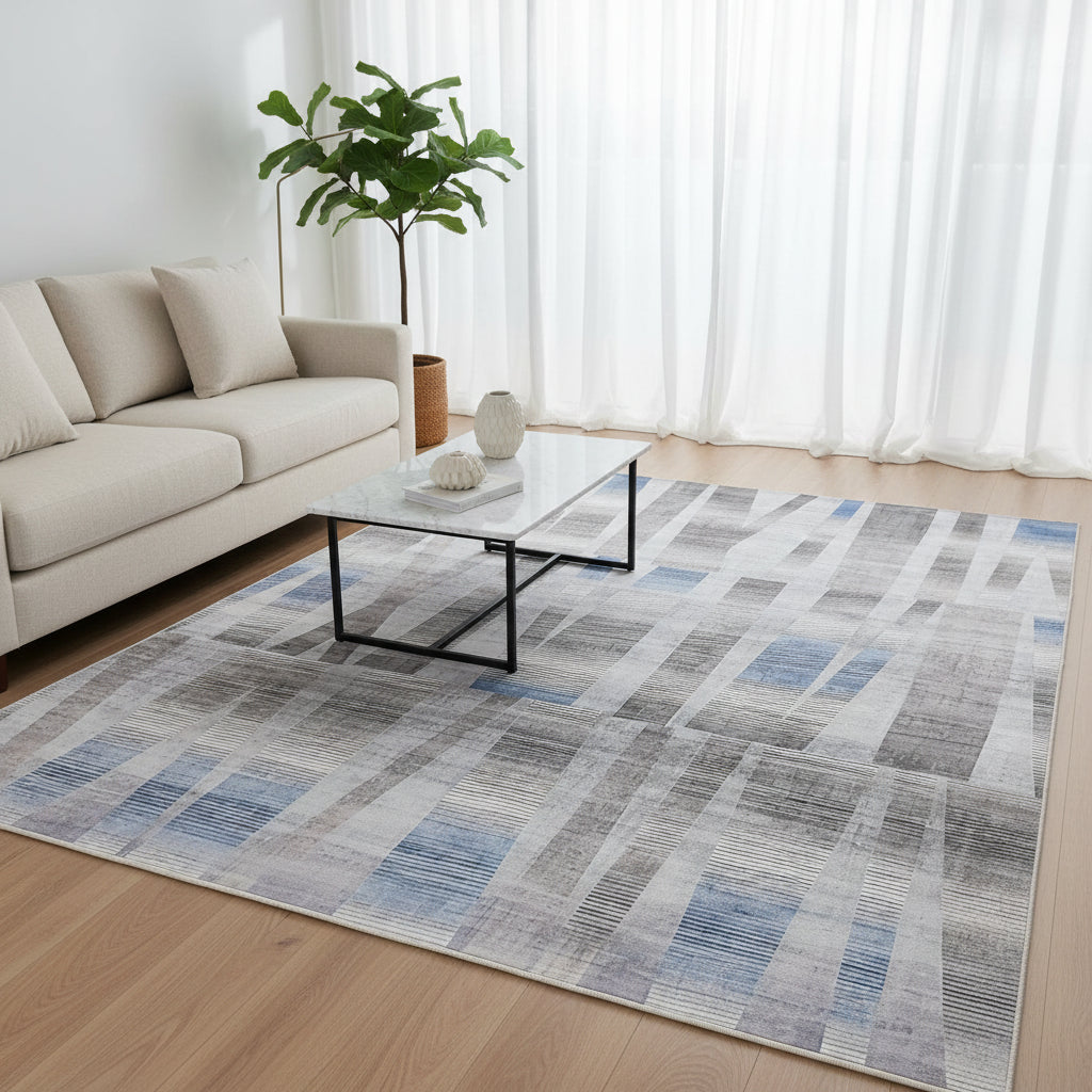An abstract area rug featuring a modern geometric pattern of vertical and horizontal striped bands in shades of blue, gray, beige, and white.