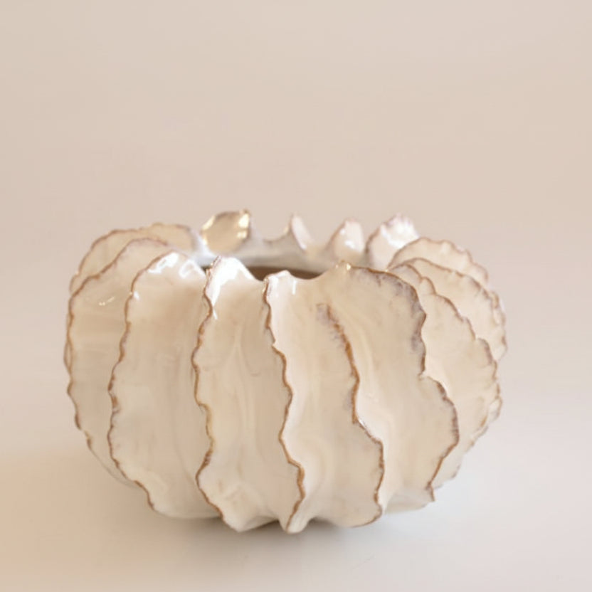 Decorative ceramic pumpkin with gold accents on a beige background