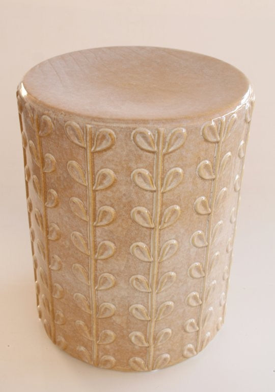 Decorative cylindrical vase with leaf pattern on a beige background