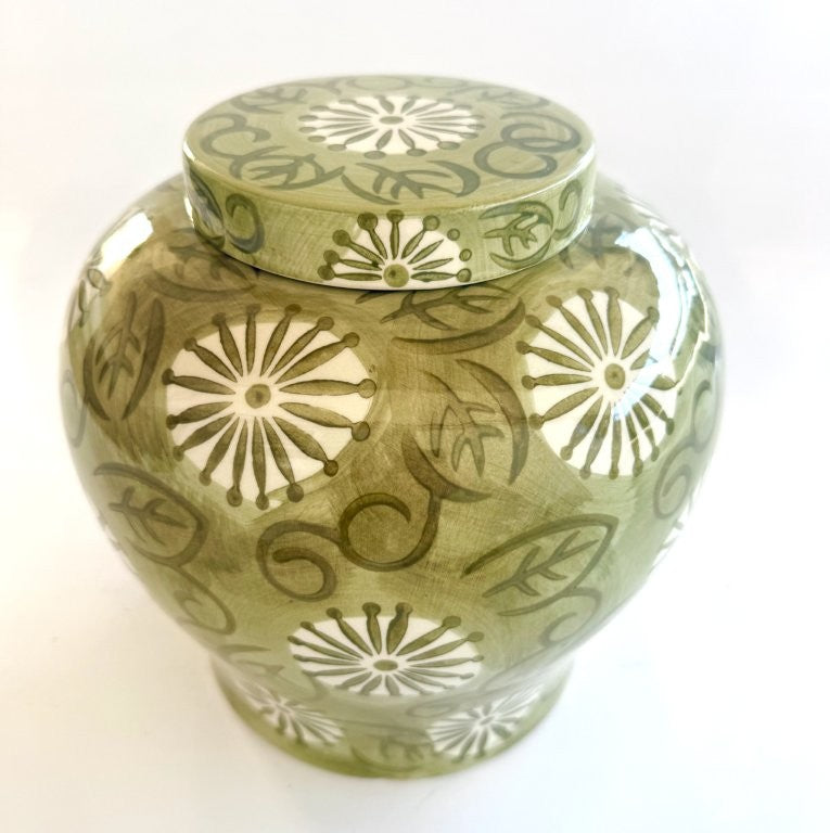 Green ceramic jar with floral patterns on a white background
