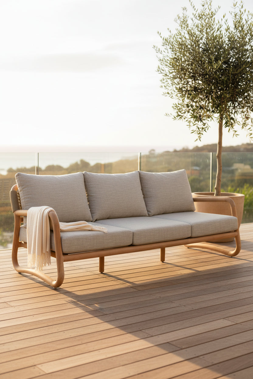 A three-seat outdoor sofa with light beige textured cushions and a curved natural wood frame, shown against a plain white background.