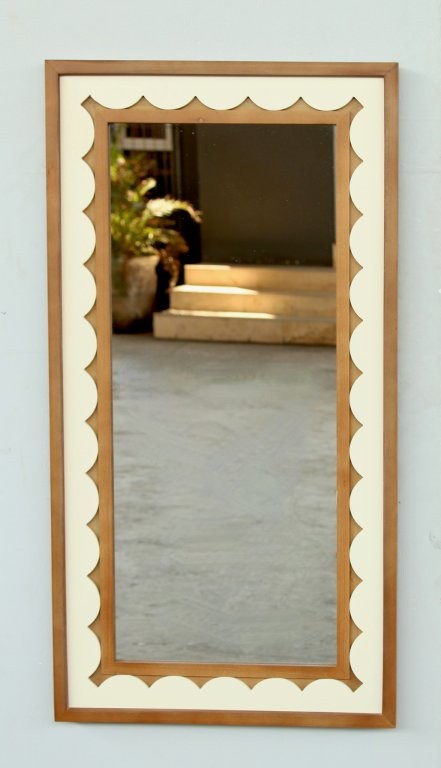 Decorative mirror with scalloped edge on a light gray wall