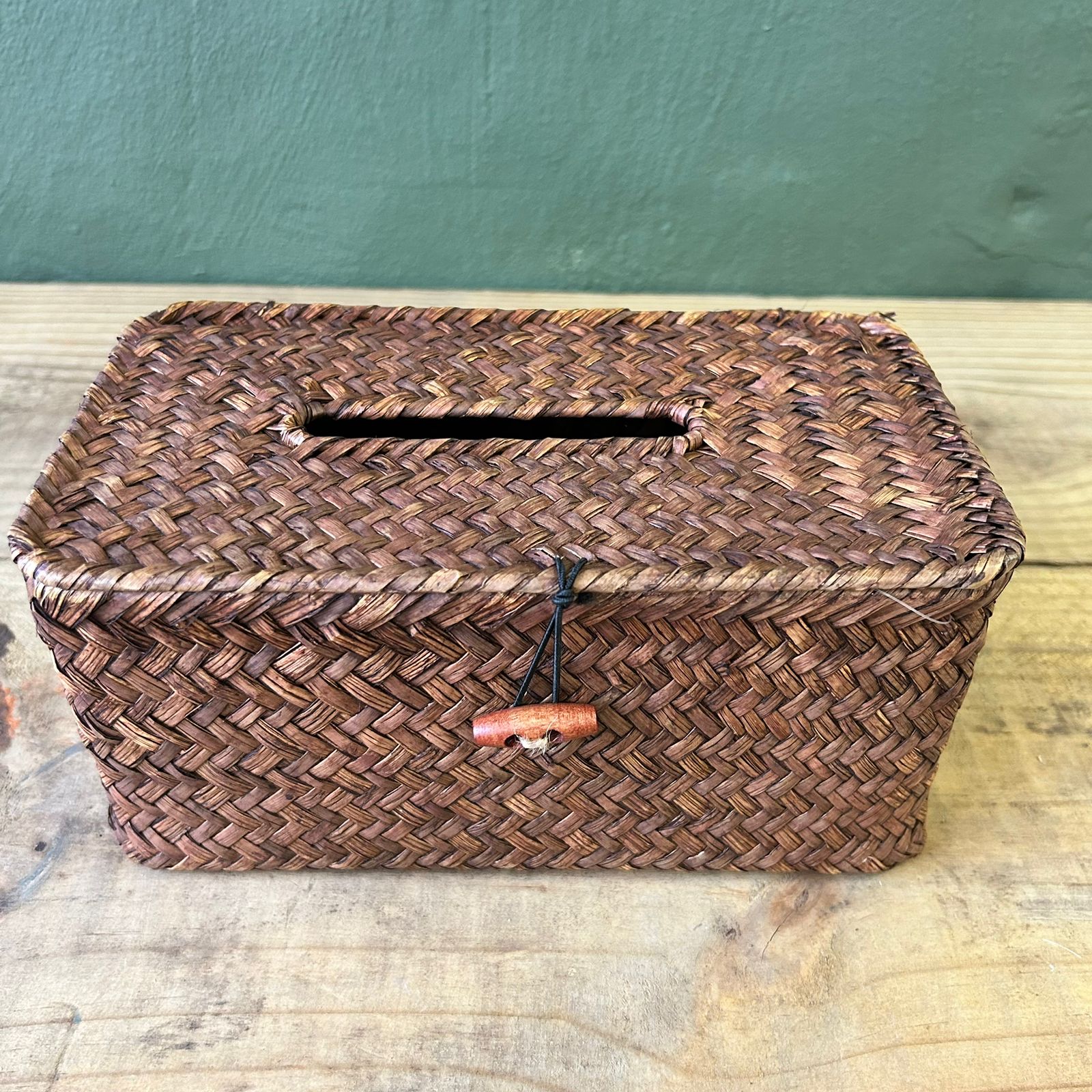 Woven brown basket with a lid on a wooden surface